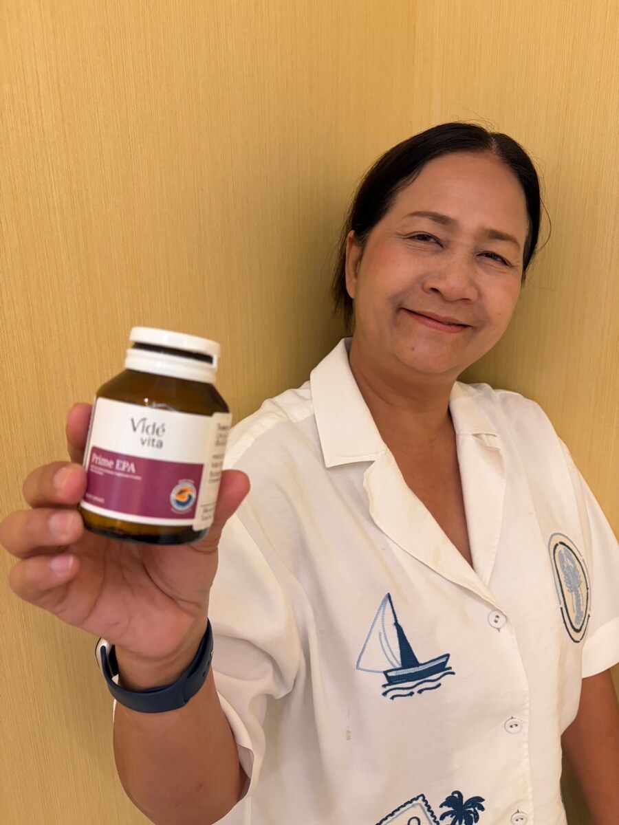 ลูกค้าหญิงถือขวด Prime EPA หน้าผนังสีเหลือง